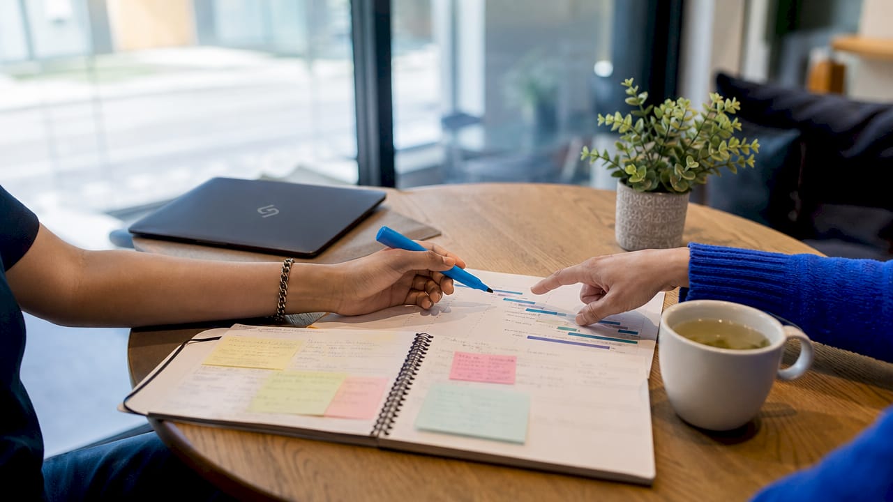 Hands pointing at calendar with notes for digital planning