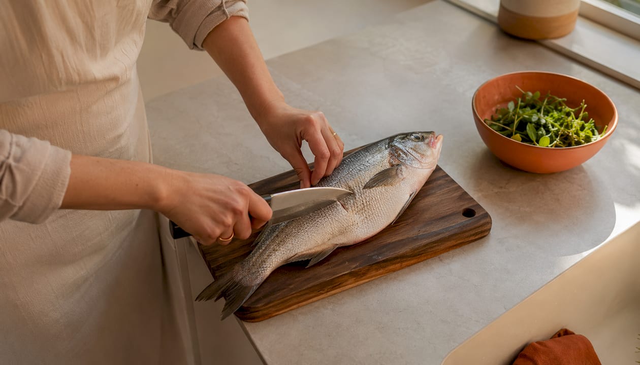 Nærbilde av fisk som fileteres med en Deba-kniv