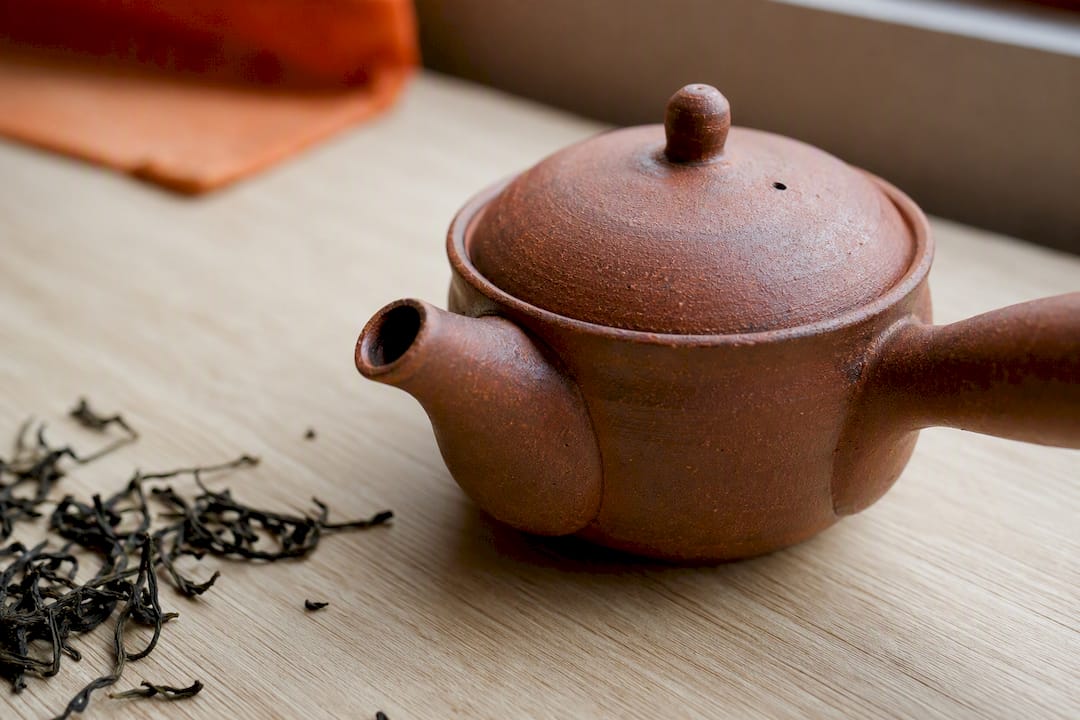 Overflaten på en rød Tokoname-kyusu har en unik struktur og føles nesten levende i hånden – med sitt varme, rødlige leirepreg gir den både visuell og taktil glede når man brygger te.