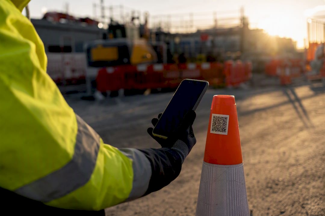 Gloved hand scanning QR code at construction site