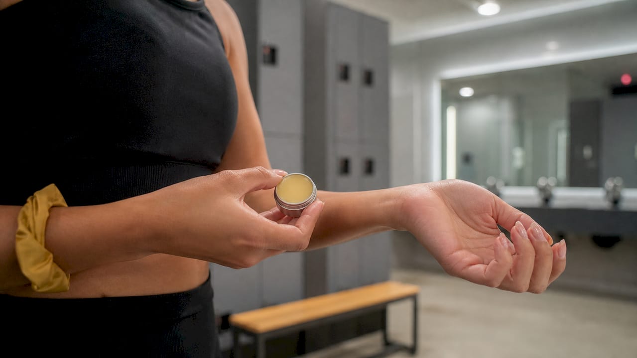 Hands applying solid perfume balm in bathroom