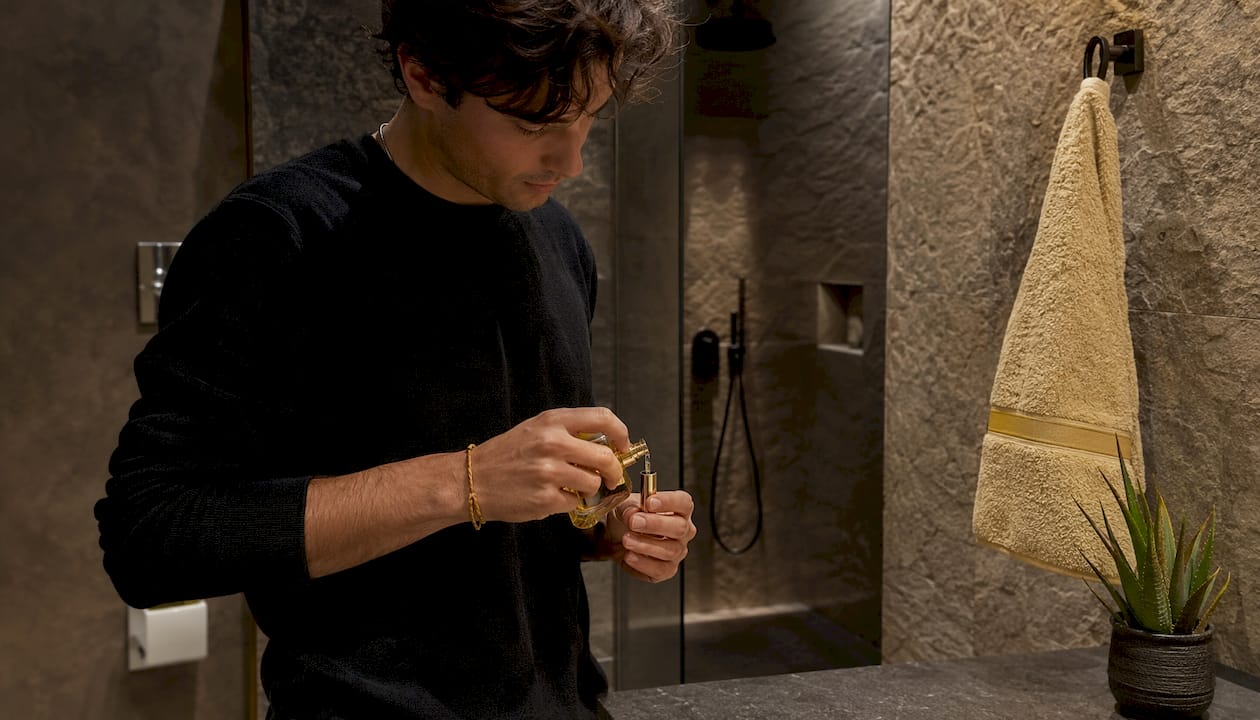 Traveler refilling mini perfume bottle in bathroom