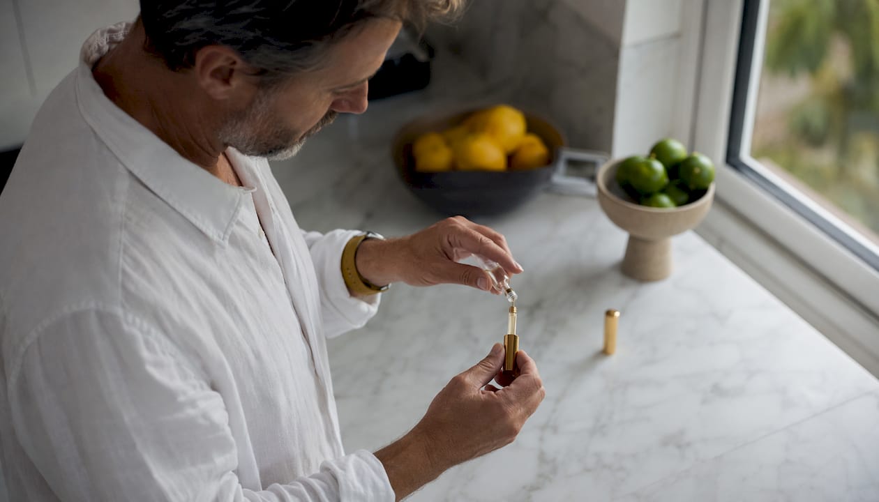 Man refilling perfume atomizer in bathroom