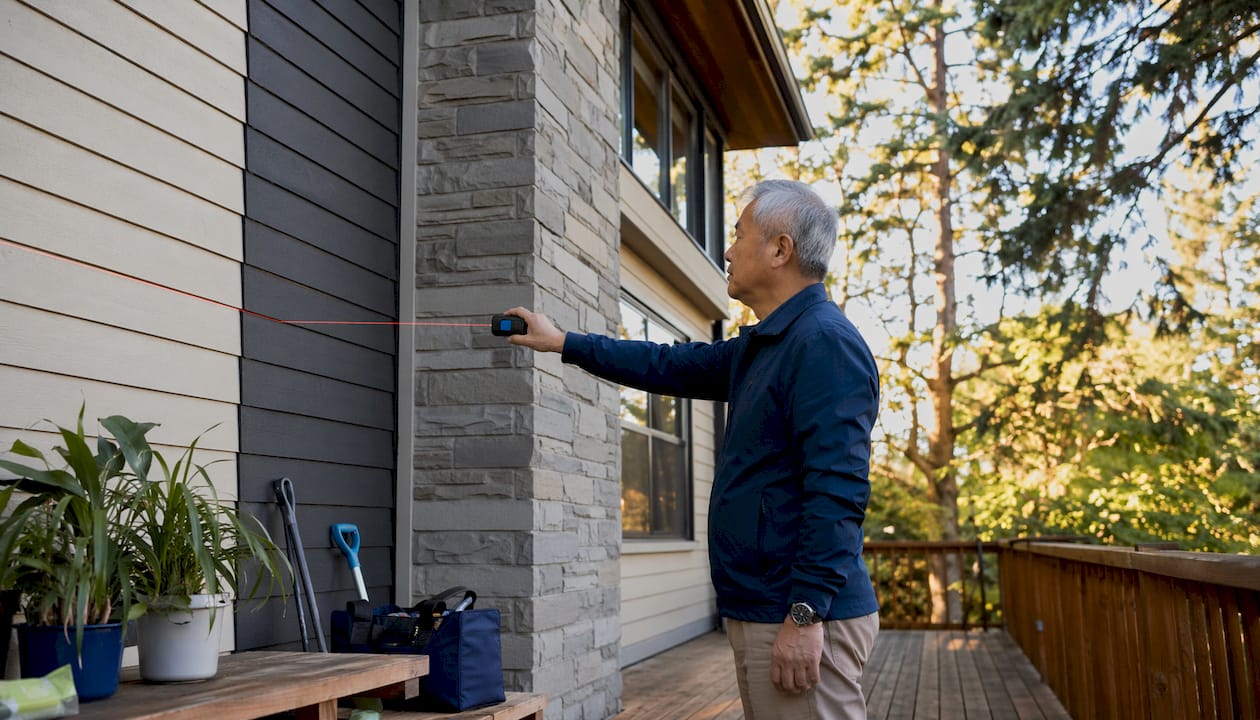 Close-up of hands measuring house exterior area