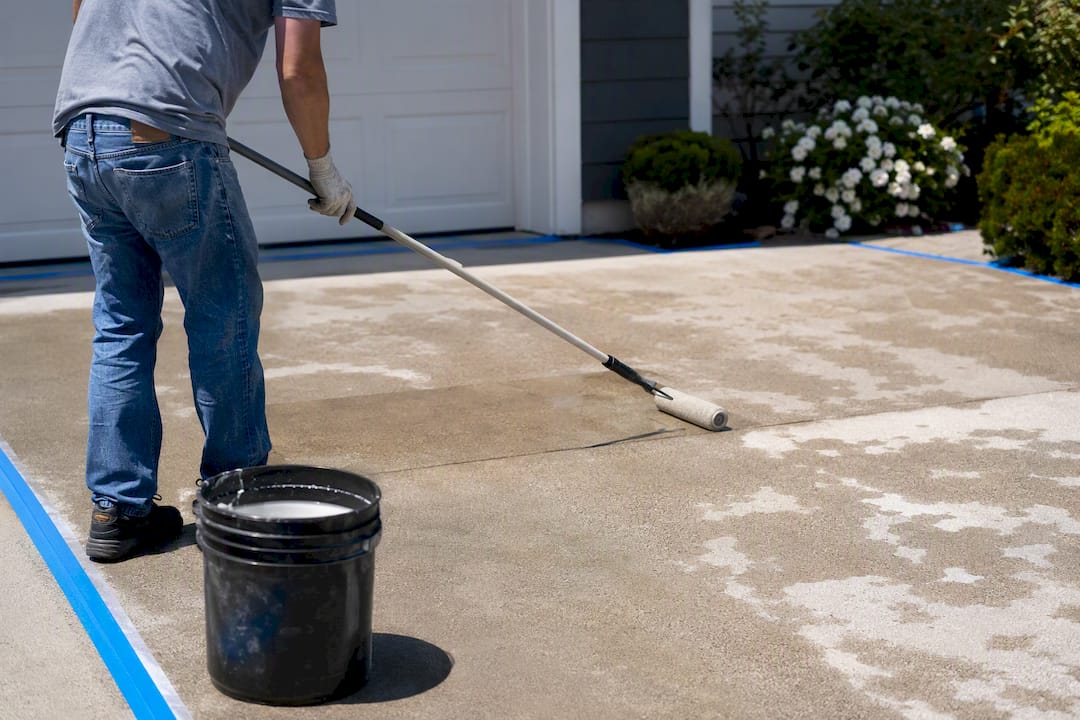 Rolling concrete sealer onto garage floor