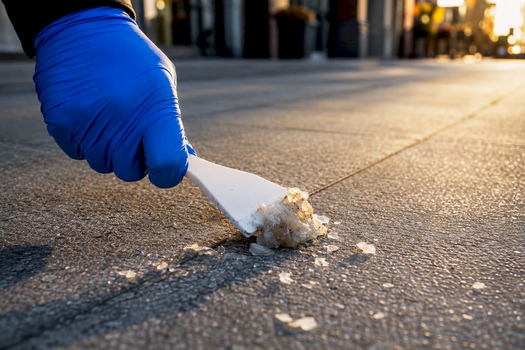 Technician scraping frozen gum from sidewalk