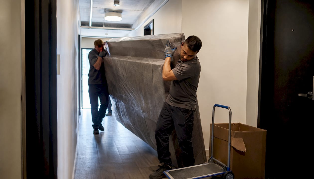 Workers moving sofa through narrow stairwell