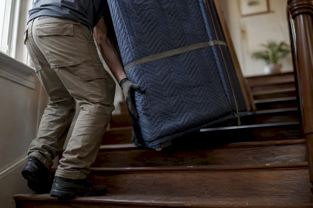 Mover lifting large item up stairs indoors