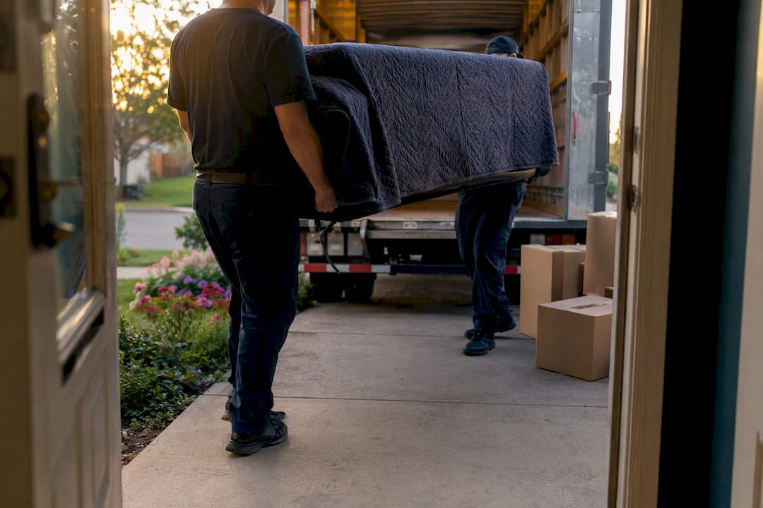 Movers carrying sofa into truck at home