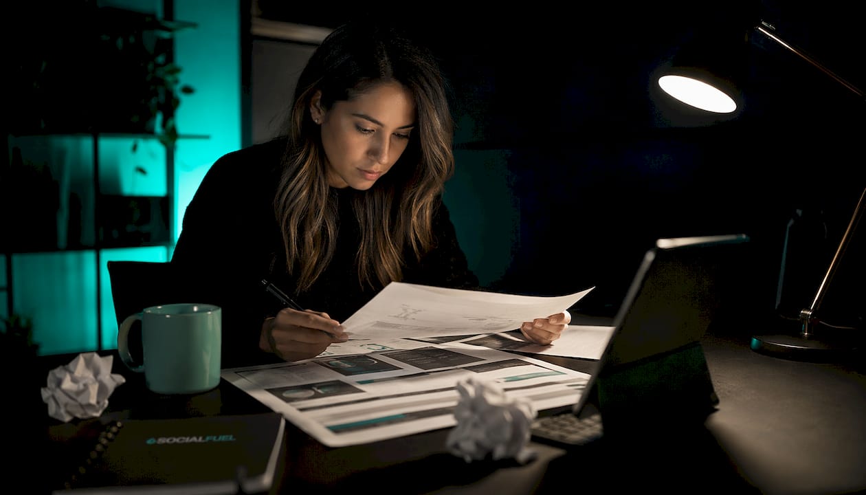 Hands typing on keyboard near tablet in dark room