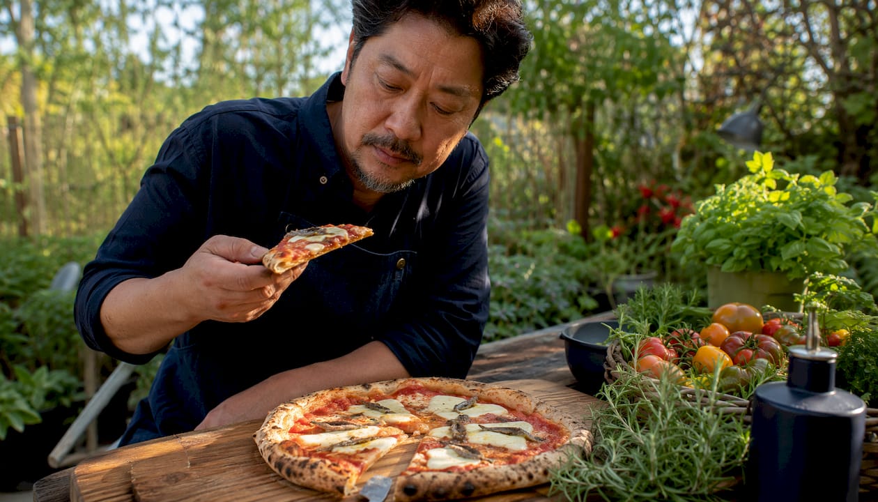 Chef tasting anchovy pizza slice in studio
