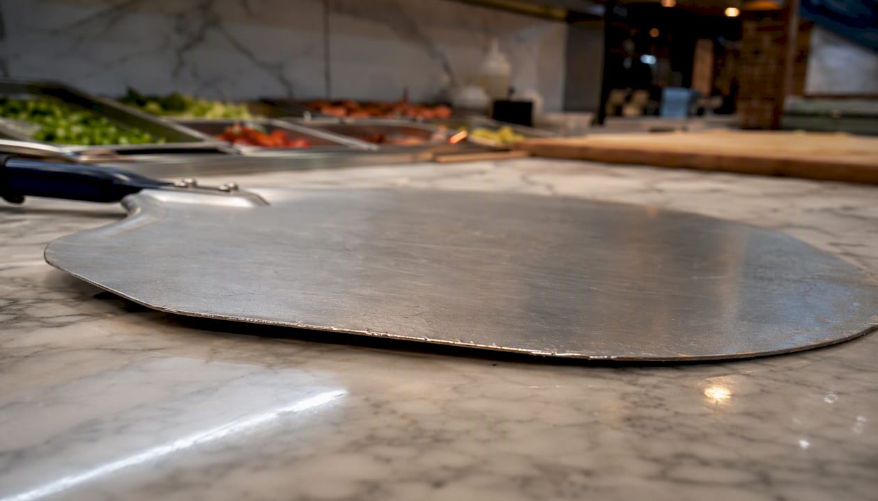 Close-up of aluminum pizza peel edge on counter