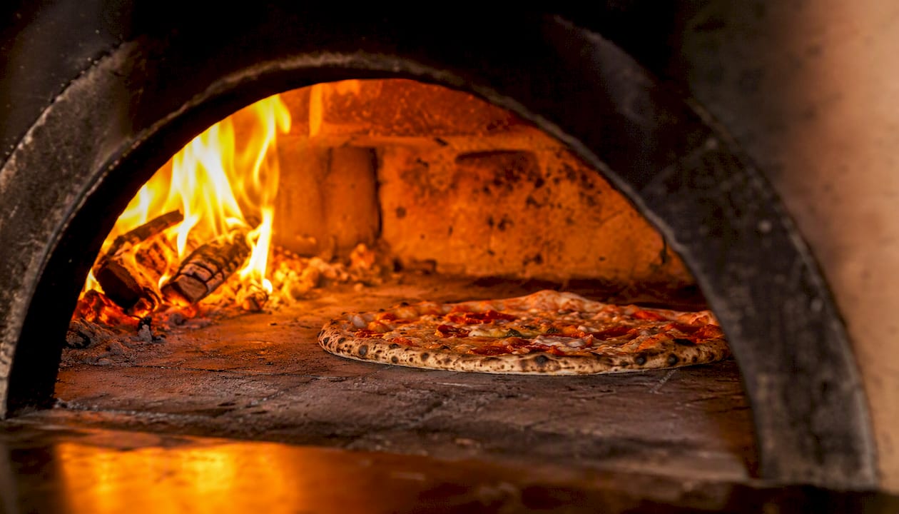 Inside wood-fired pizza oven with pizza baking