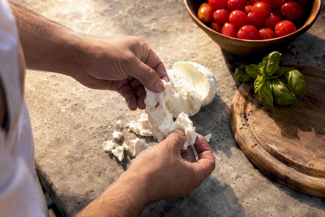 Hands tearing fresh mozzarella cheese