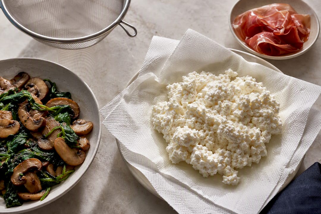 Draining ricotta beside sautéed pizza toppings