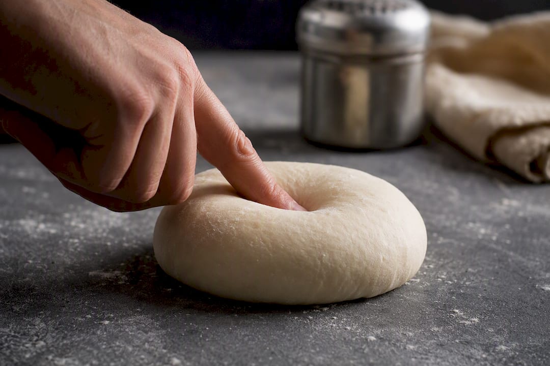 Finger pressing rested pizza dough