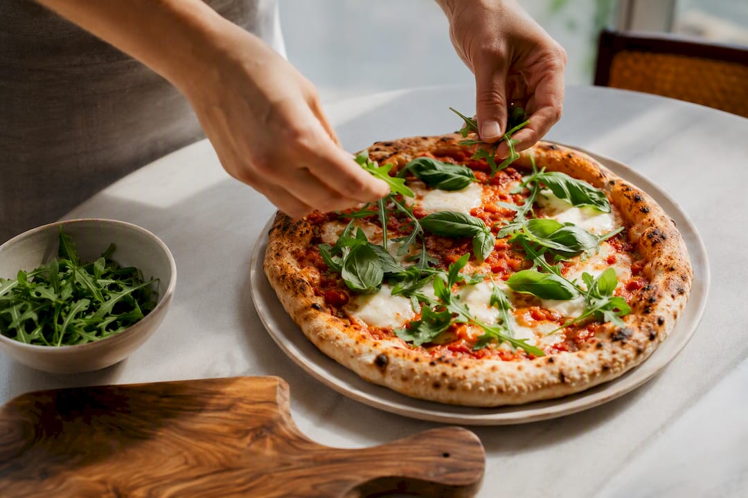 Fresh basil and rocket added to pizza