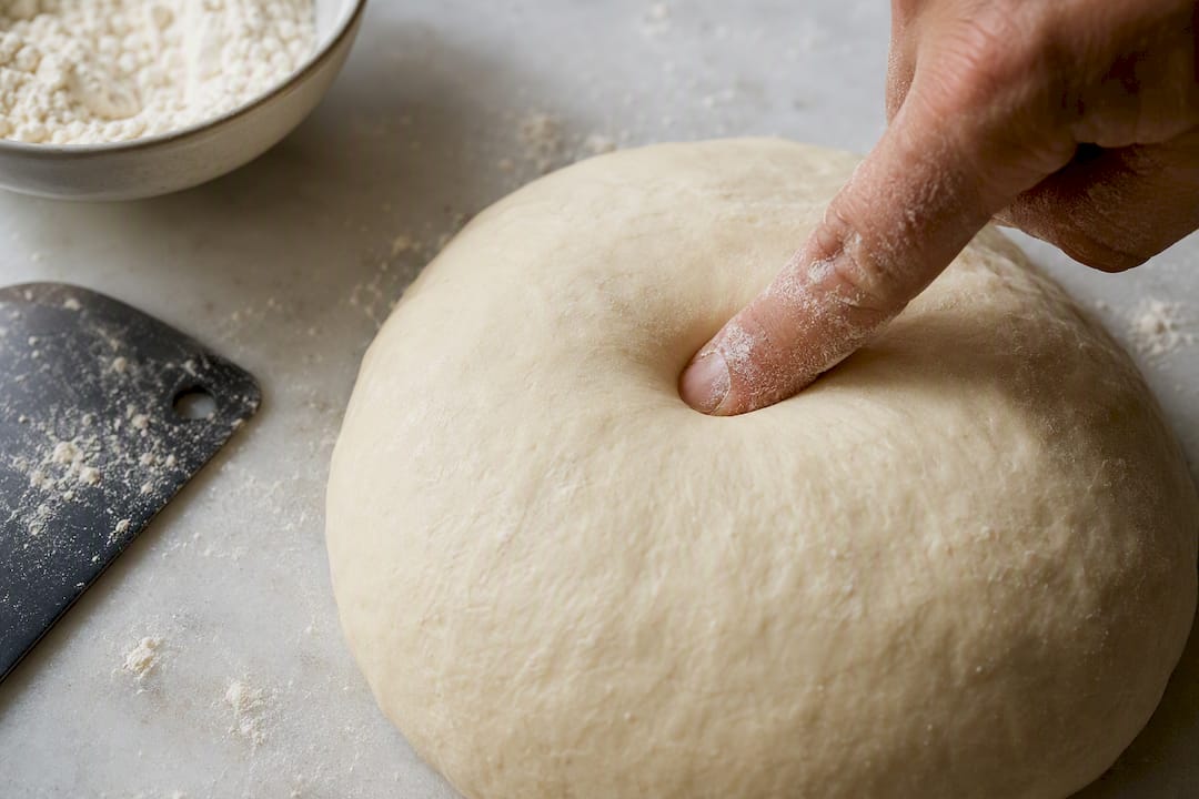 Finger testing a pizza dough indentation