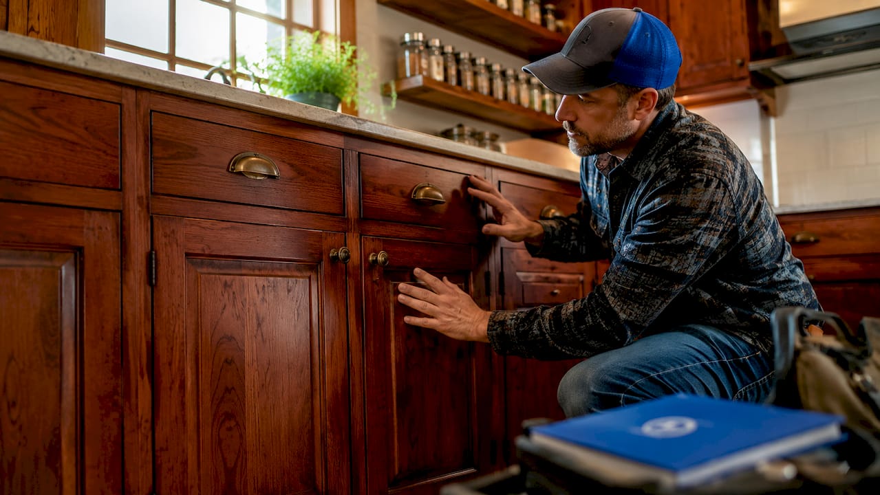 Hands inspecting raised-panel cherry cabinet doors