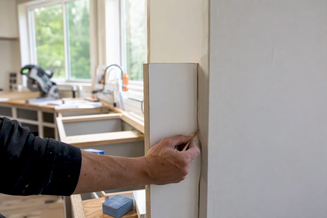 Using scribe tool to mark cabinet panel for uneven wall