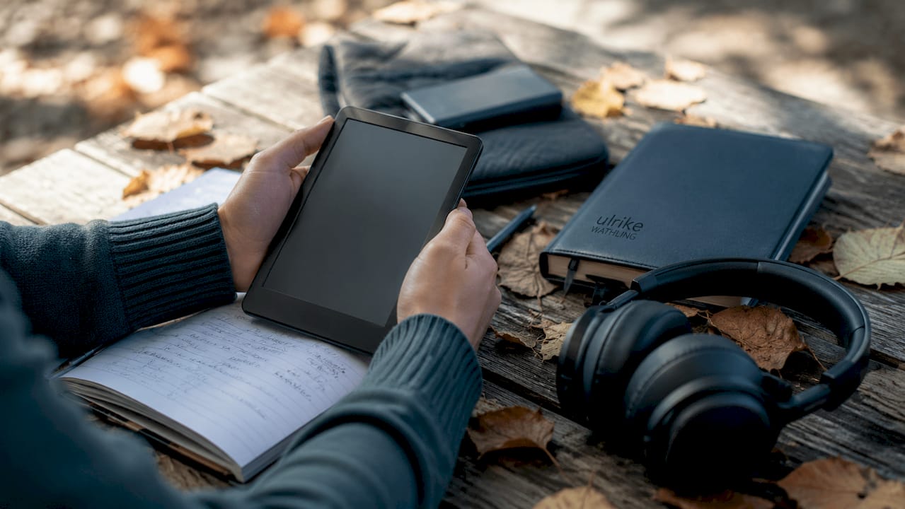 Jemand hält einen E-Reader in den Händen und testet neugierig das neue Technik-Geschenk zum Geburtstag.