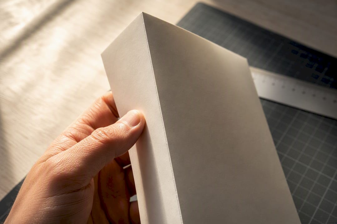 Die Papierkante einer Karte wird gegen das Licht gehalten