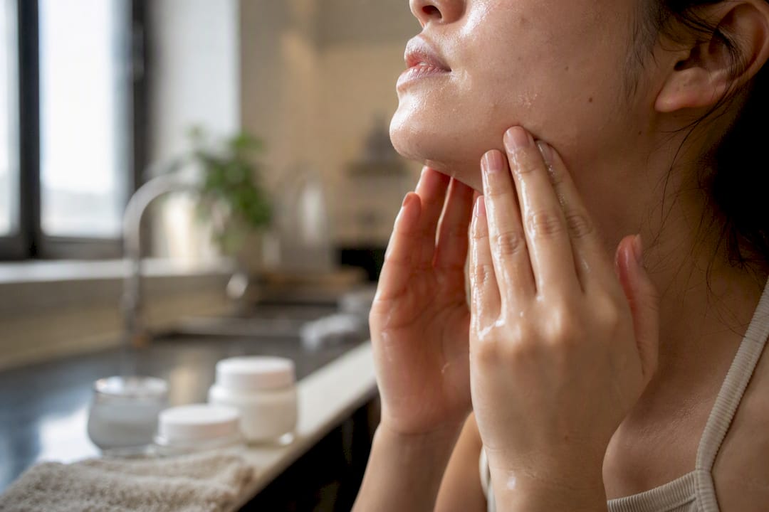 Hand massaging damp skin with serum