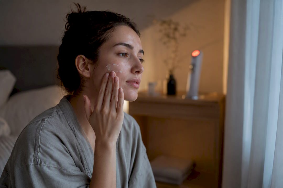 Hand applying gel near LED skincare device silhouette