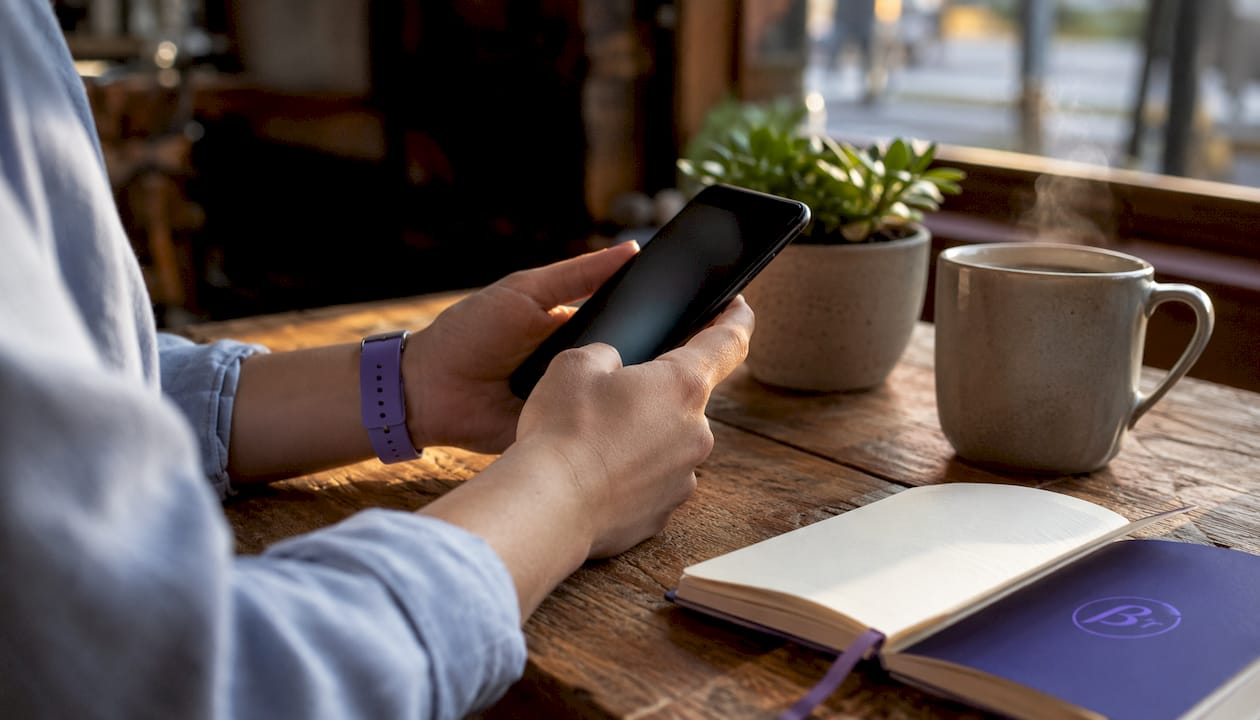 Hands holding smartphone in home office