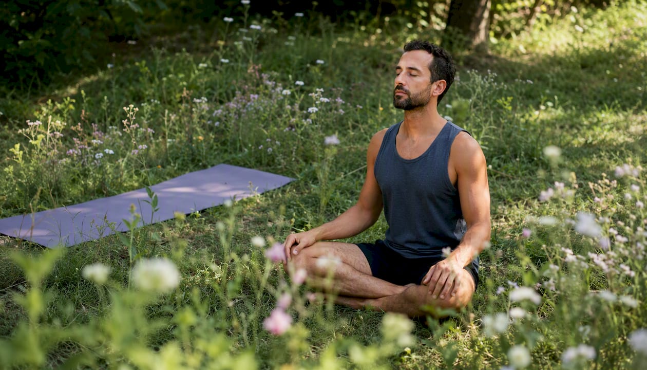 Man meditating outdoors for stress relief