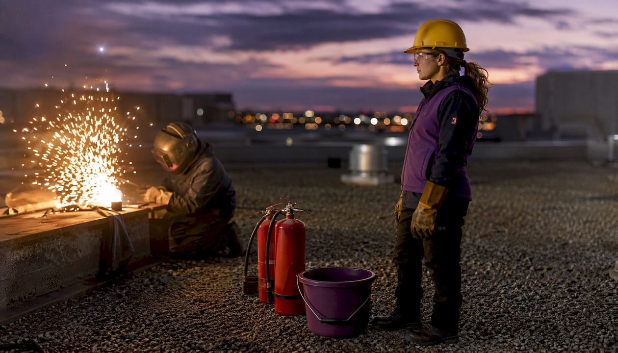 Fire watch worker monitoring welding sparks outdoors