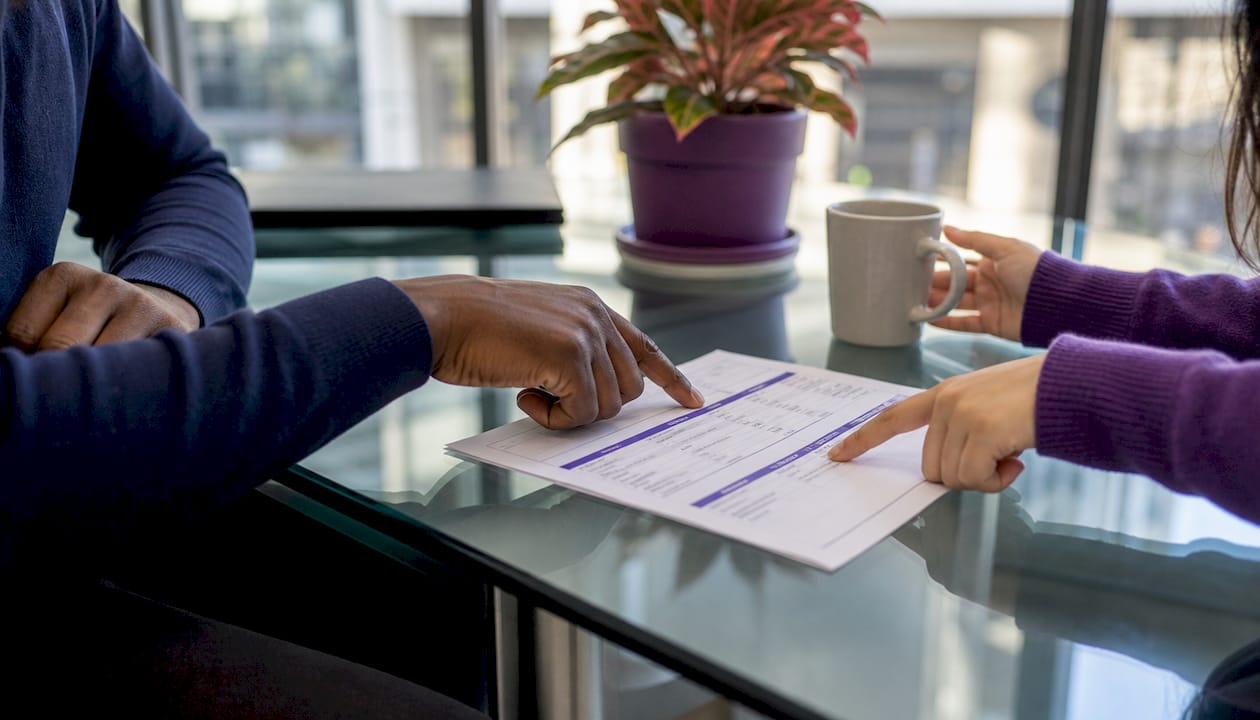 Hands pointing at Amazon intern pay spreadsheet printout