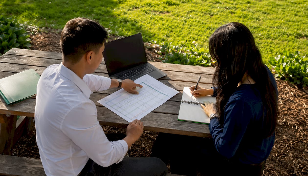 Hands collaborating on Excel practice worksheet in meeting room