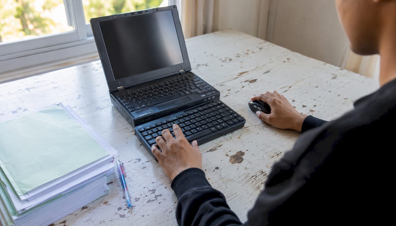 Hands navigating PDF on older Windows laptop