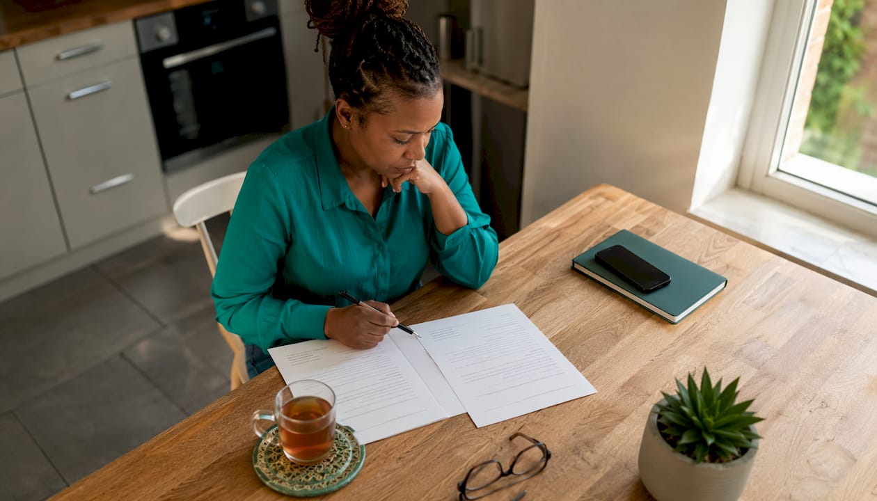 Woman reviewing job offer paperwork at home desk