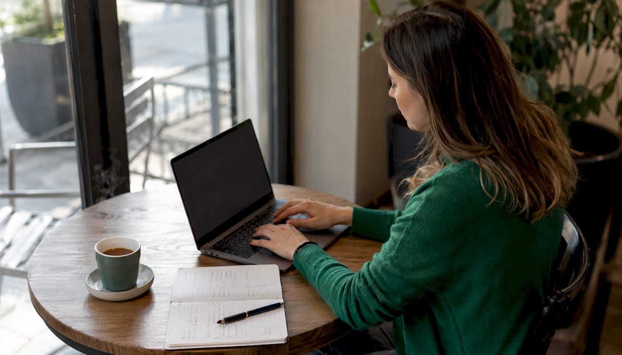 Eine berufstätige Frau sitzt im Homeoffice und arbeitet konzentriert an ihrem Laptop.