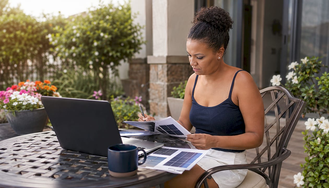 Woman studying solar panel brochures at home