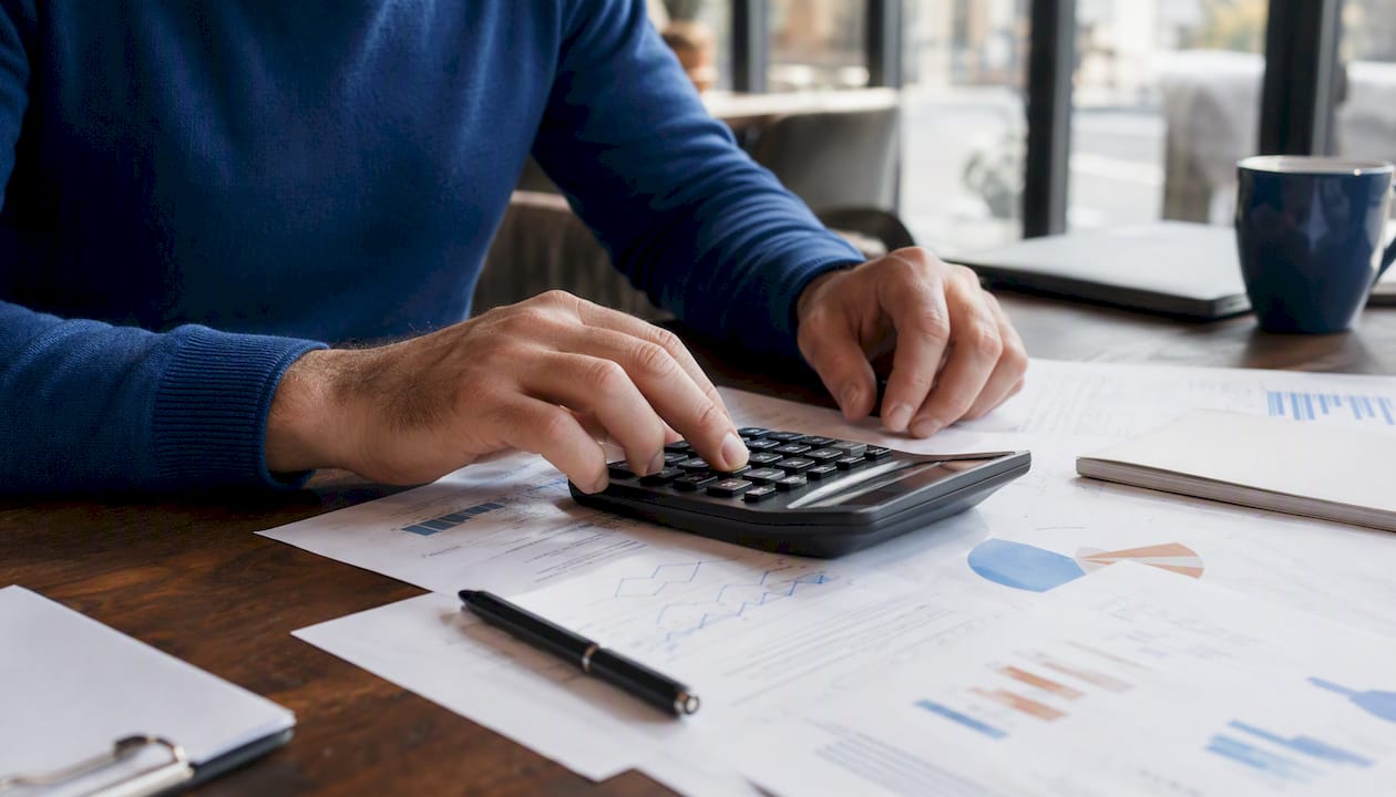 Mani maschili che inseriscono mese e giorno su una calcolatrice per ottenere il codice fiscale.