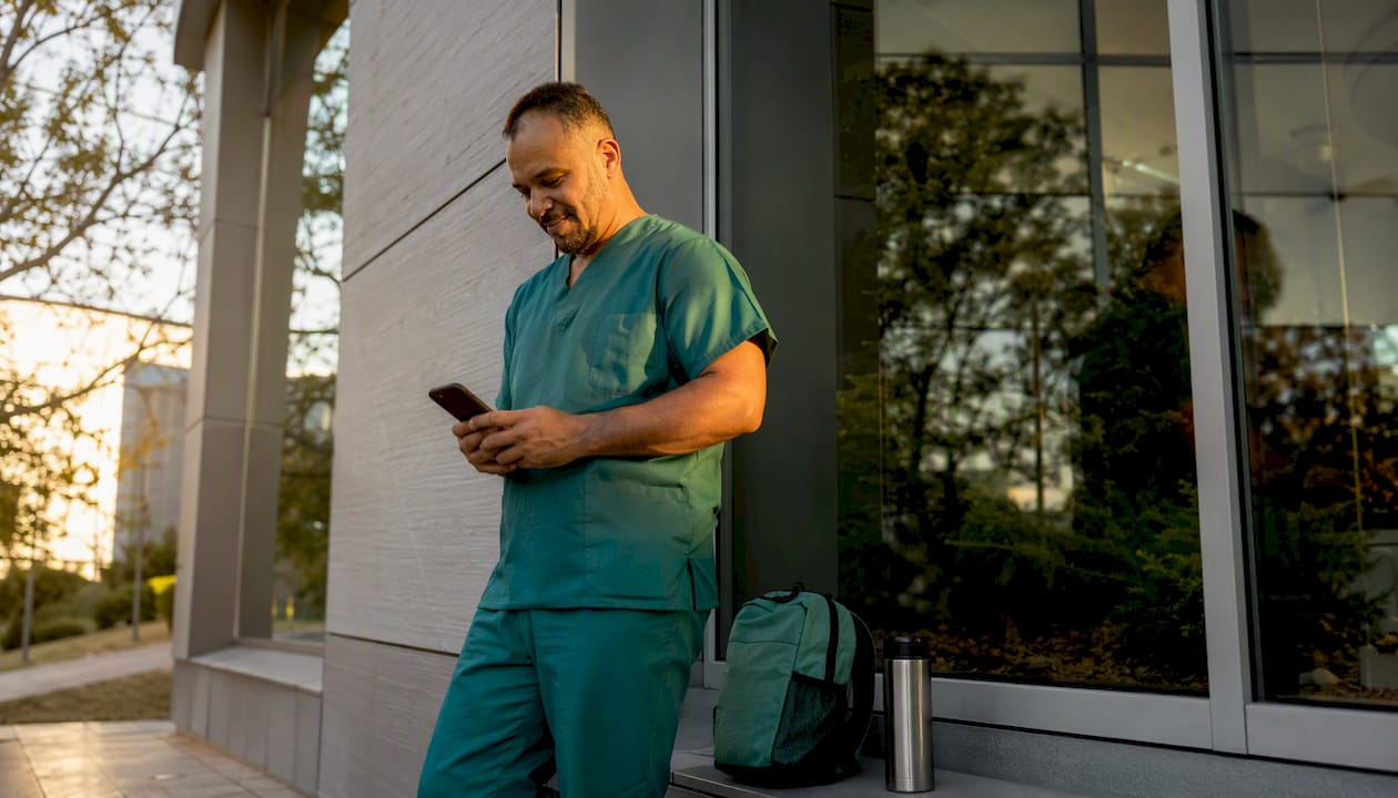 Nurse checking WhatsApp job alerts outdoors