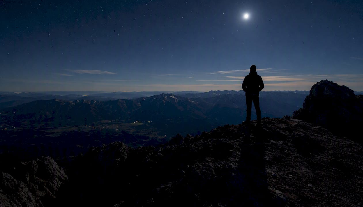 La sagoma di una sentinella che veglia sulla cresta della montagna, immersa nell’oscurità della notte.