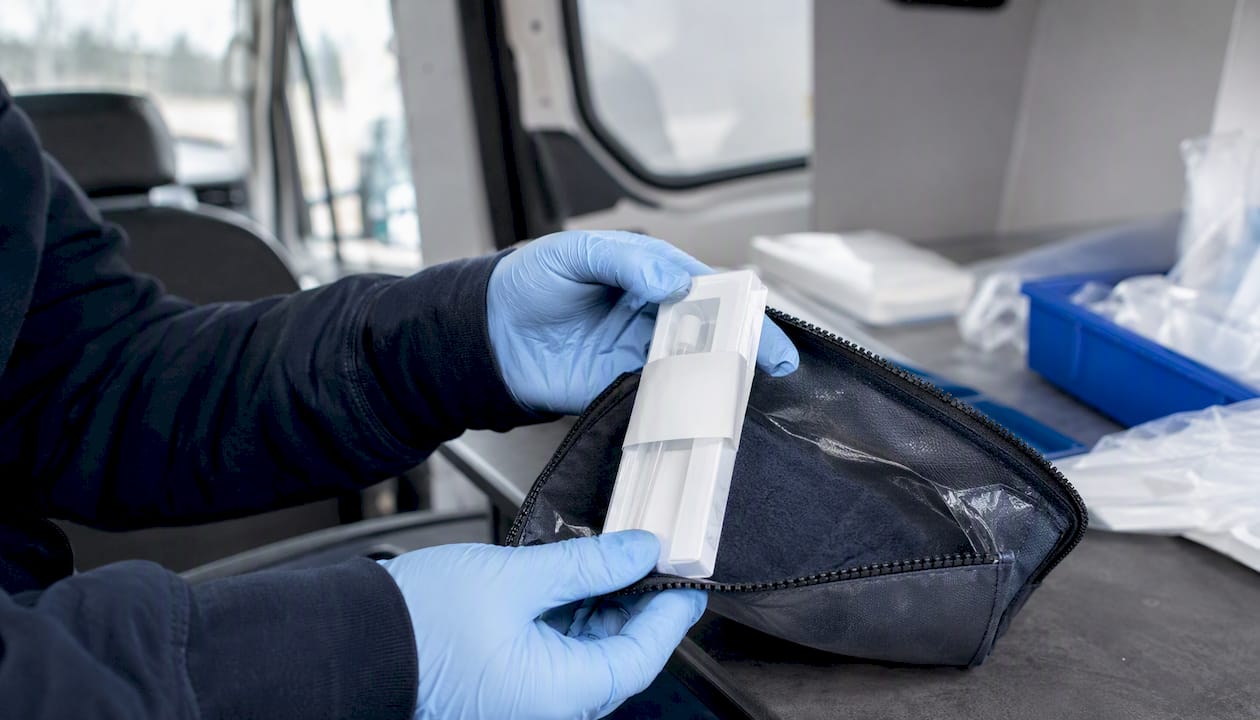 Gloved hands packaging DNA evidence kit