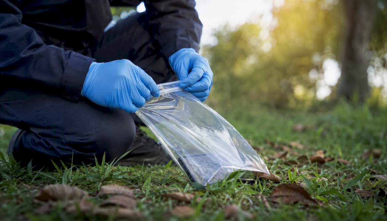 Hands sealing evidence bag in forensic lab