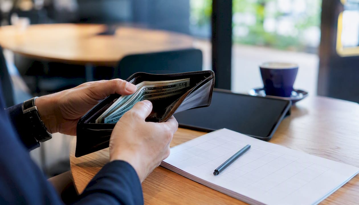Hands holding wallet over budgeting sheet