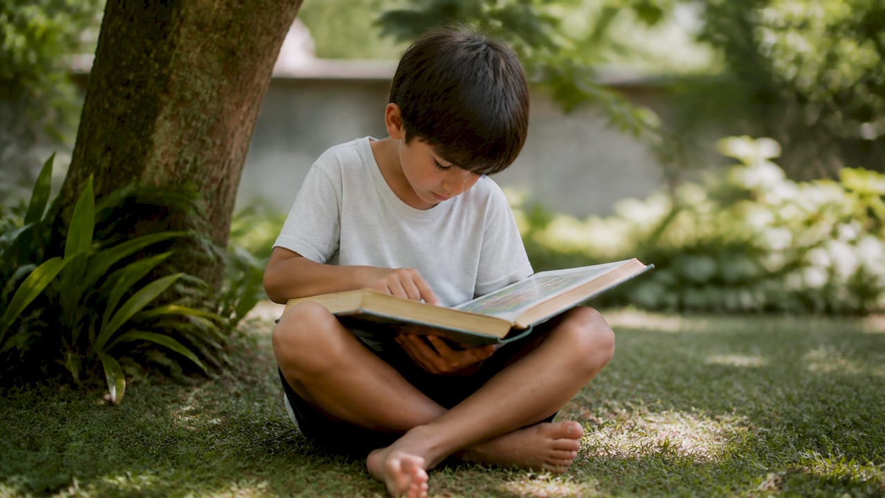 Un niño disfruta de la lectura de la Biblia en plena naturaleza.