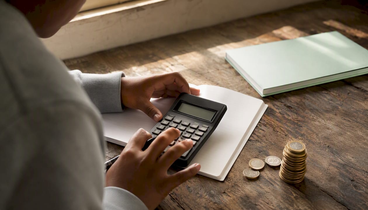 Hands calculating finance maths with calculator and coins