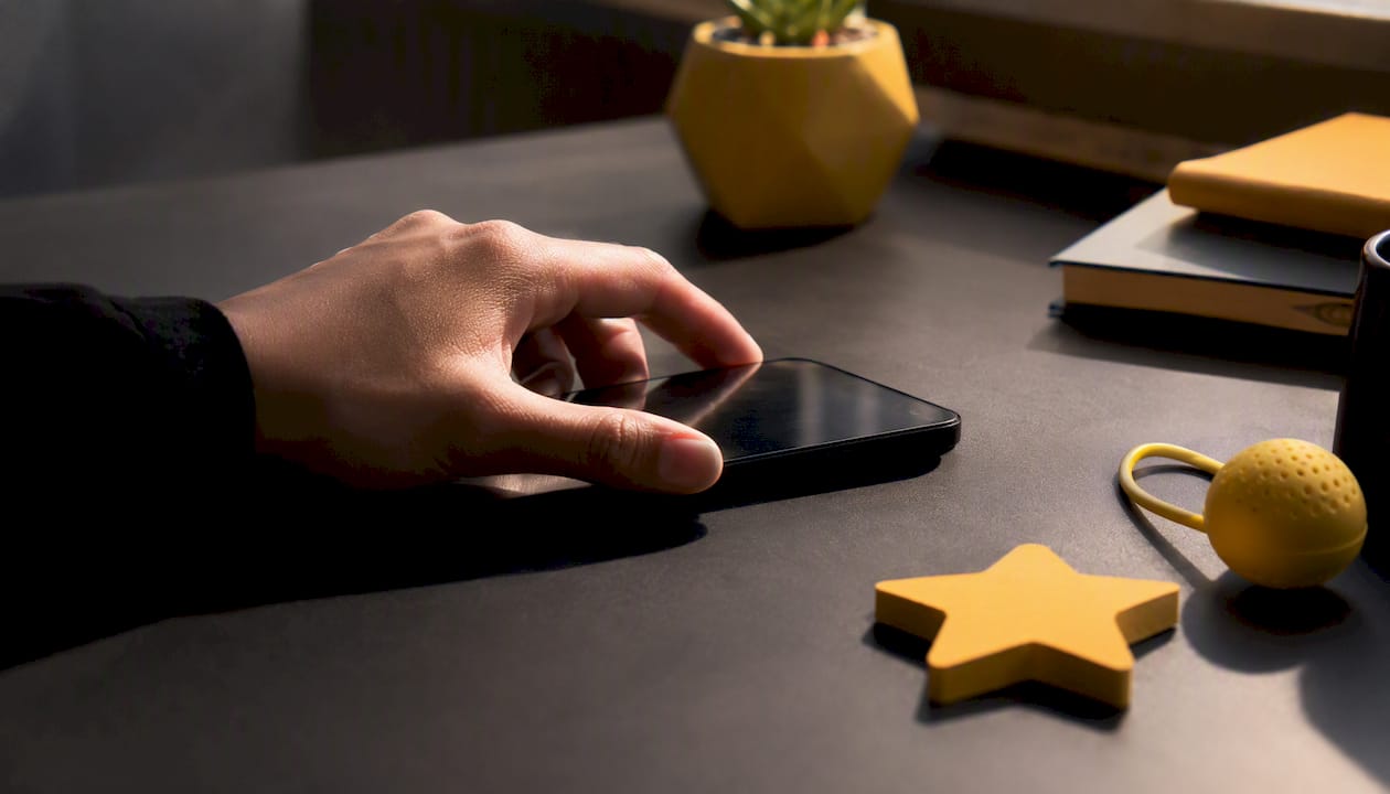 Hand holding smartphone over dark surface with star props