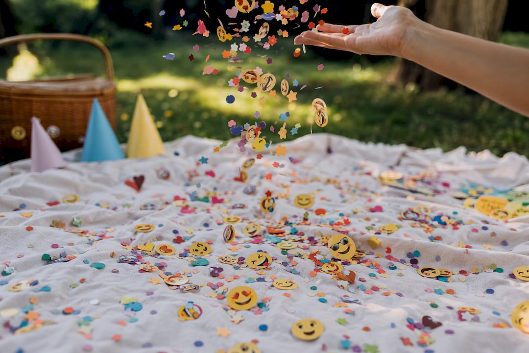 Hand scattering birthday emoji confetti