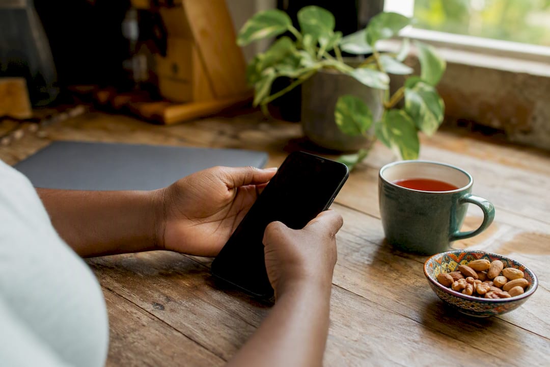 Hands holding smartphone with WhatsApp on home table