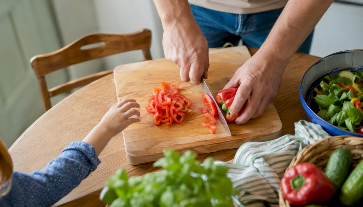 Mani che cucinano mentre una manina di bambino si avvicina curiosa