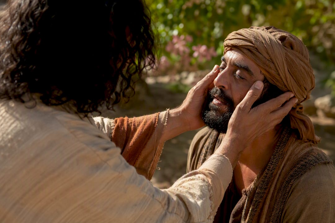 Hands healing man in biblical setting